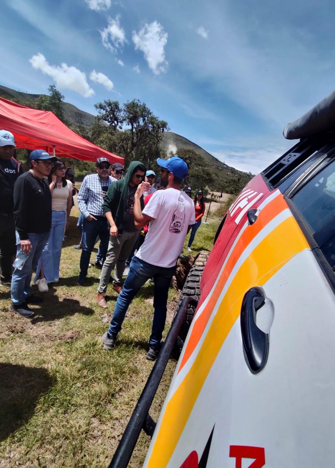 Asesores comerciales recibiendo instrucciones junto a un vehículo del evento